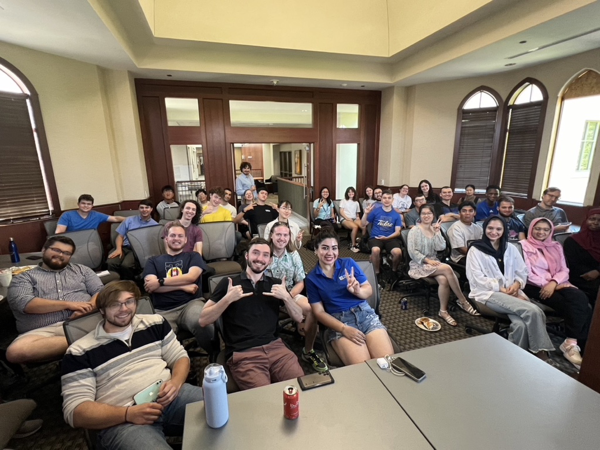 A full room of AIML@TU members smiling and waving at a lunch-and-learn meeting