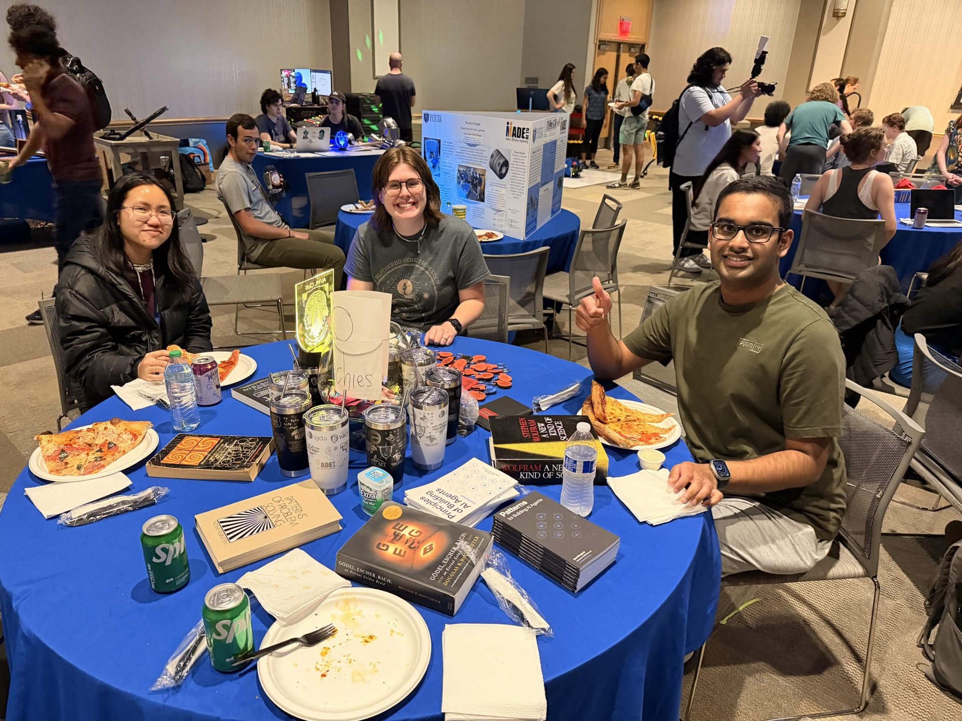 Students at the AIML@TU table during Multi-Club Mashup III, with pizza, books and a glowing club sign