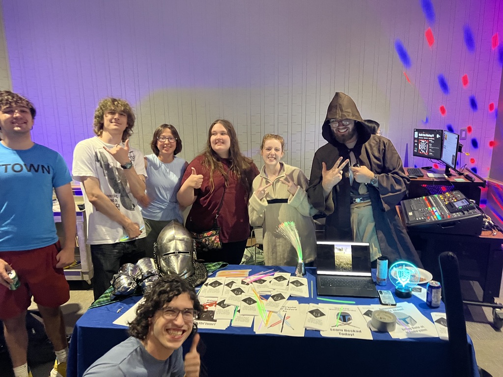 The HAMA crew in costume around their table, with a knight's helmet, a hooded Jedi and lots of thumbs up